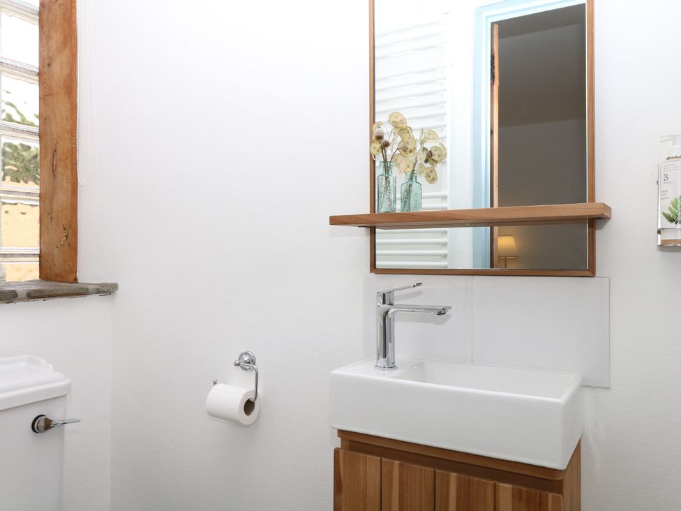 A bathroom with a sink, toilet, and mirror at Burrows in Venn Ottery near Sidmouth