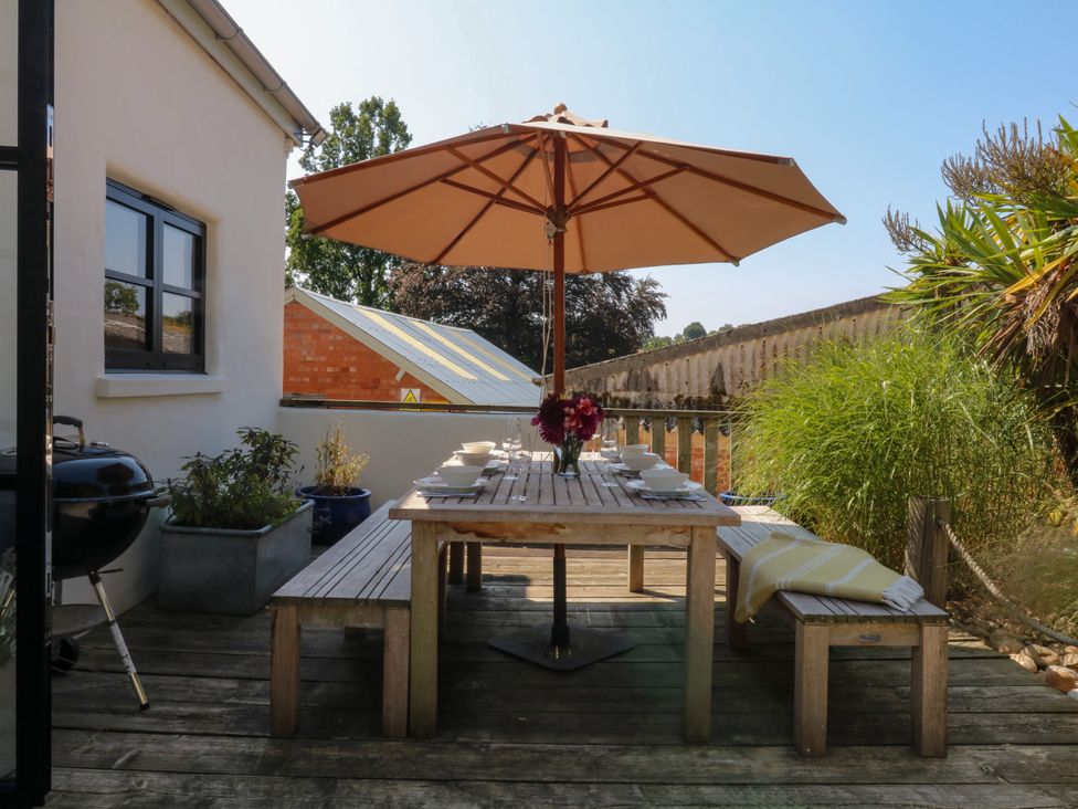 An outdoor dining setup with a wooden table and umbrella at Burrows Venn Ottery near Sidmouth