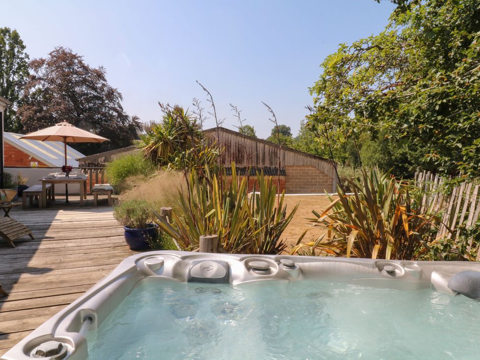 An outdoor area with a hot tub and a wooden deck at Burrows in Venn Ottery near Sidmouth