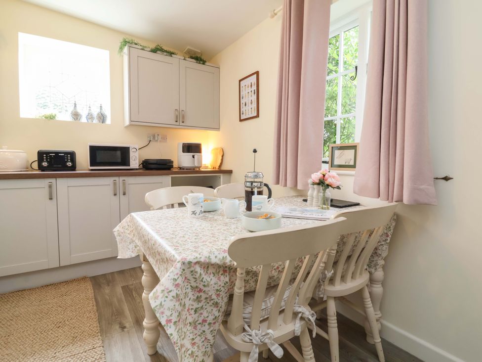 A kitchen with a dining table and appliances at Sunset Cottage in Swimbridge near Barnstaple