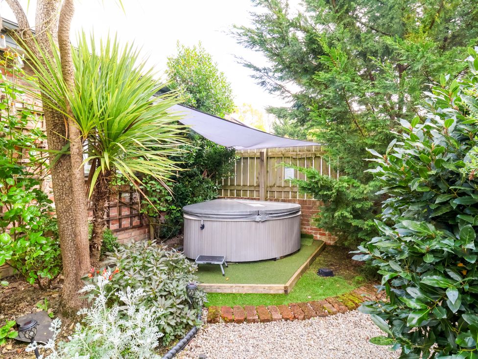 A garden with a hot tub and trees at Sunset Cottage in Swimbridge near Barnstaple