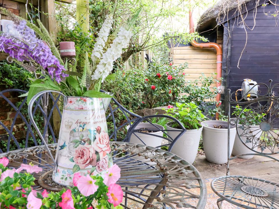 A garden with a table and flower jug at Sunset Cottage Swimbridge near Barnstaple