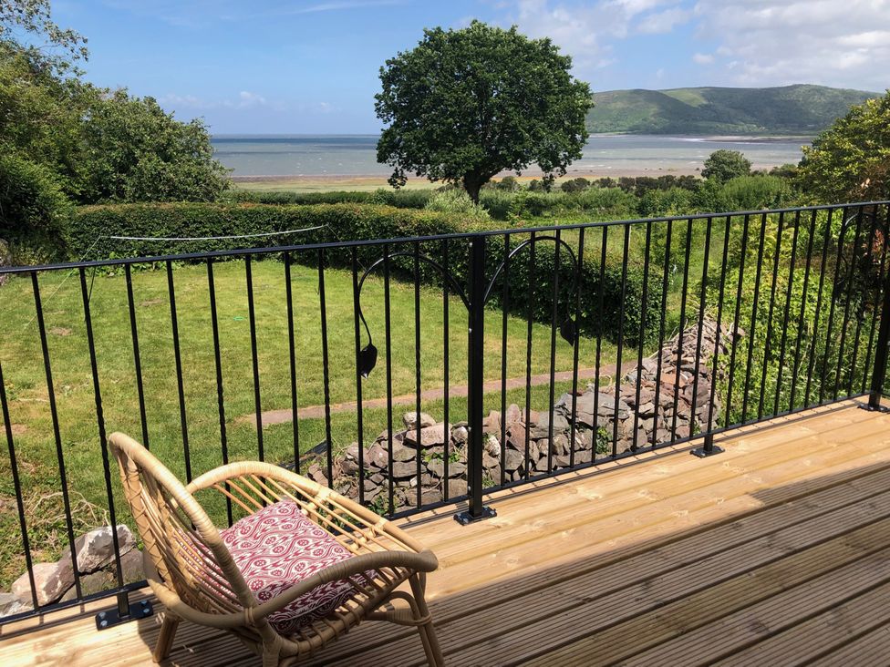 A balcony with a chair and a view of the garden at Worthy Barn in Porlock Weir