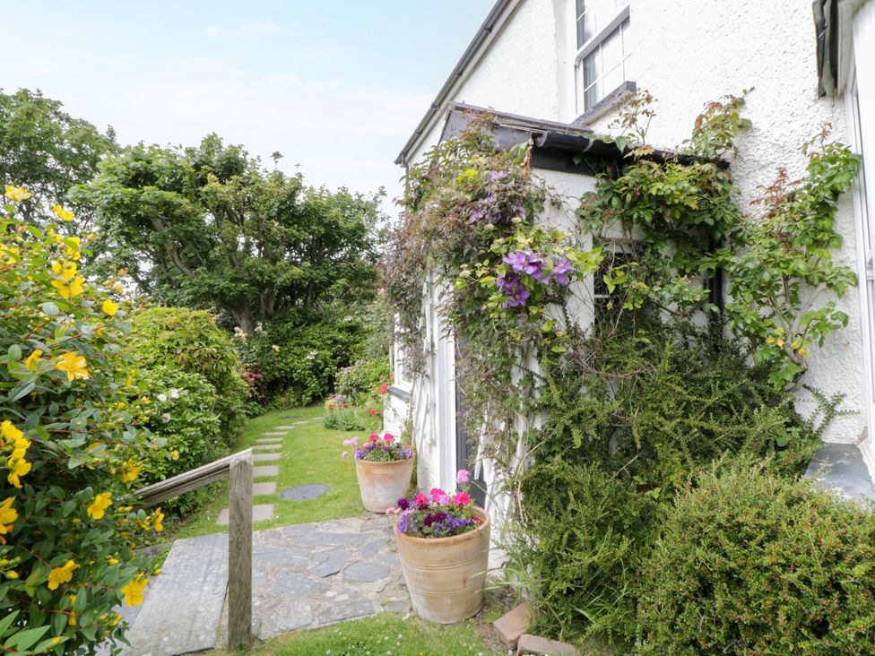 A garden with a pathway and flower pots at Pen y Graig Aberporth