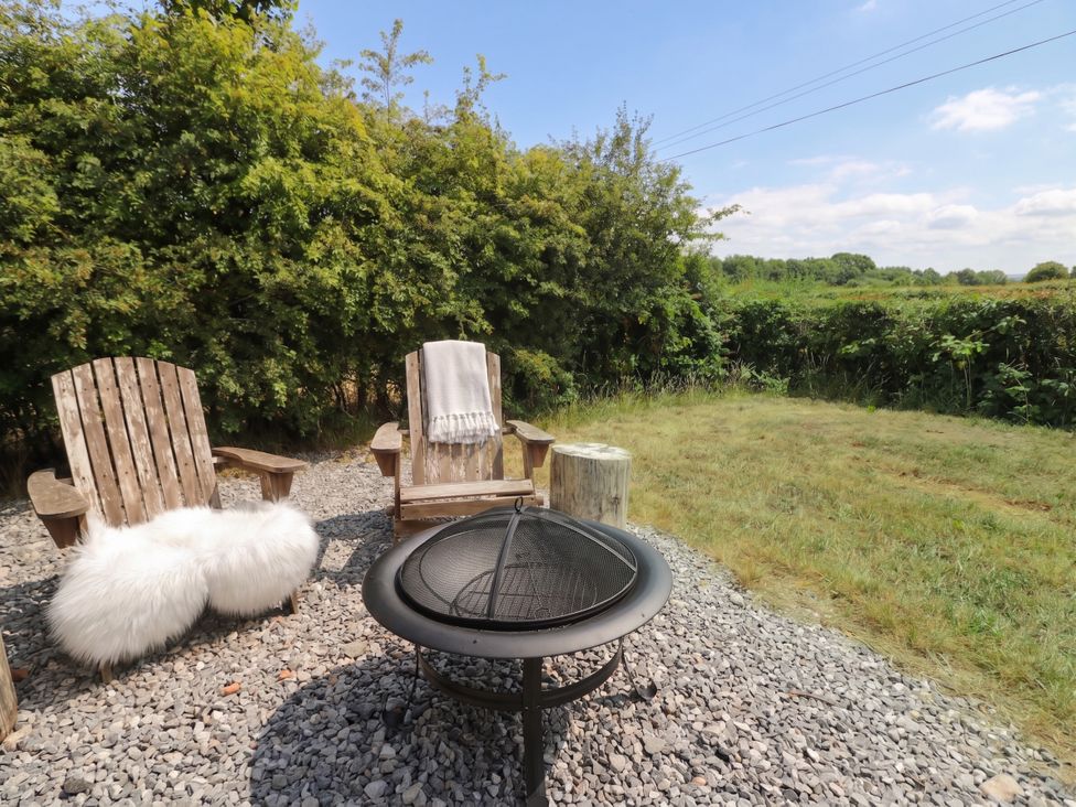 A fire pit and chairs arranged in a garden at Cariad Mawr in Gwaenysgor near Prestatyn