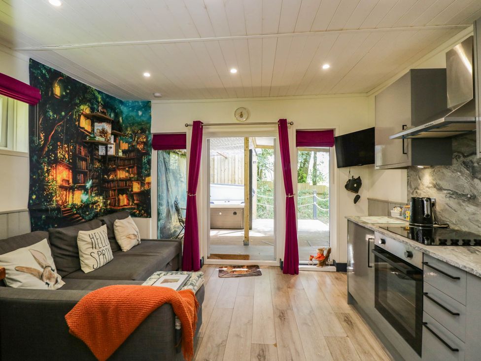 A living room with a sofa and kitchen area at Squirrels Lodge in South Molton