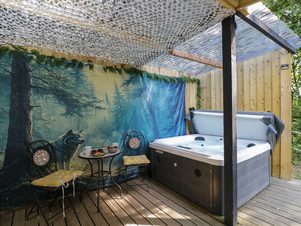 An outdoor seating area with a hot tub and a table with chairs at Squirrels Lodge in South Molton