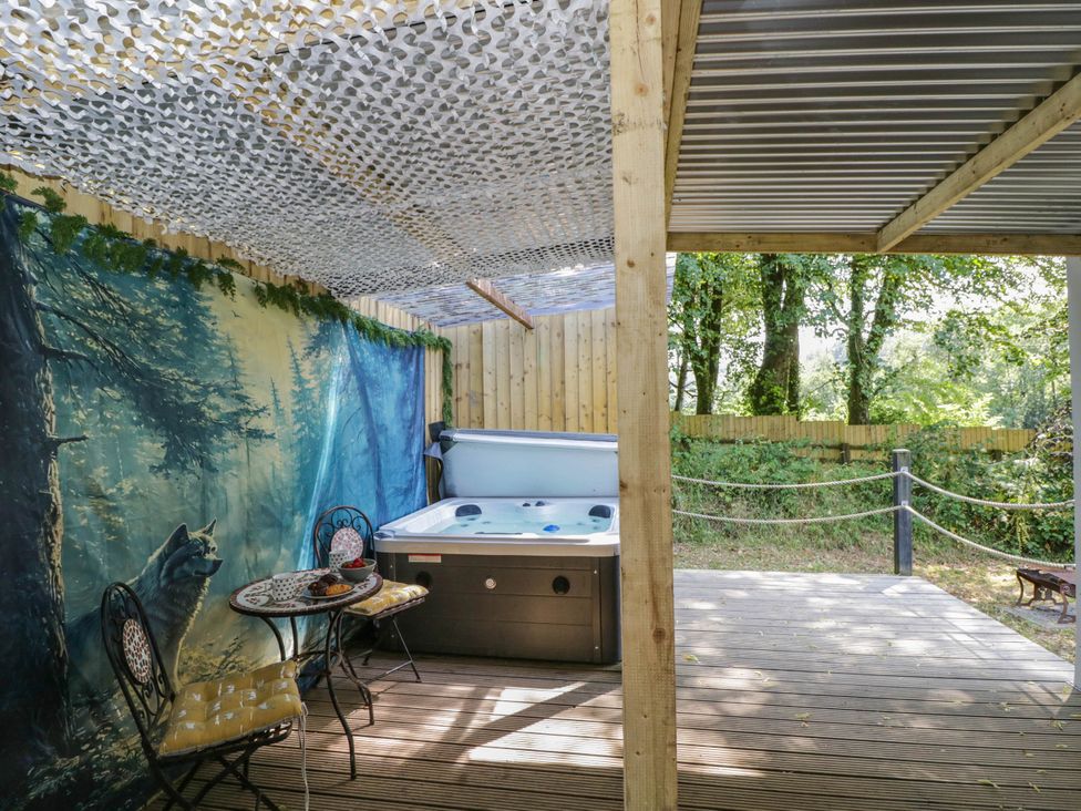 An outdoor patio featuring a hot tub and seating at Squirrels Lodge in South Molton