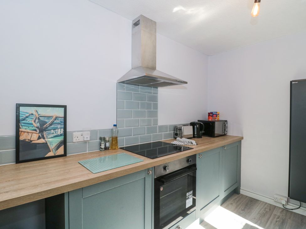 A kitchen with a countertop, stove, and fridge at Stones Throw in Lymington