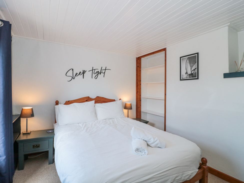 A bedroom with a bed and nightstands at Stones Throw in Lymington
