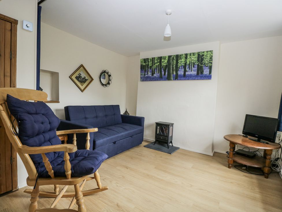 A living room with a sofa bed and rocking chair at Woods Cottage near Raglan