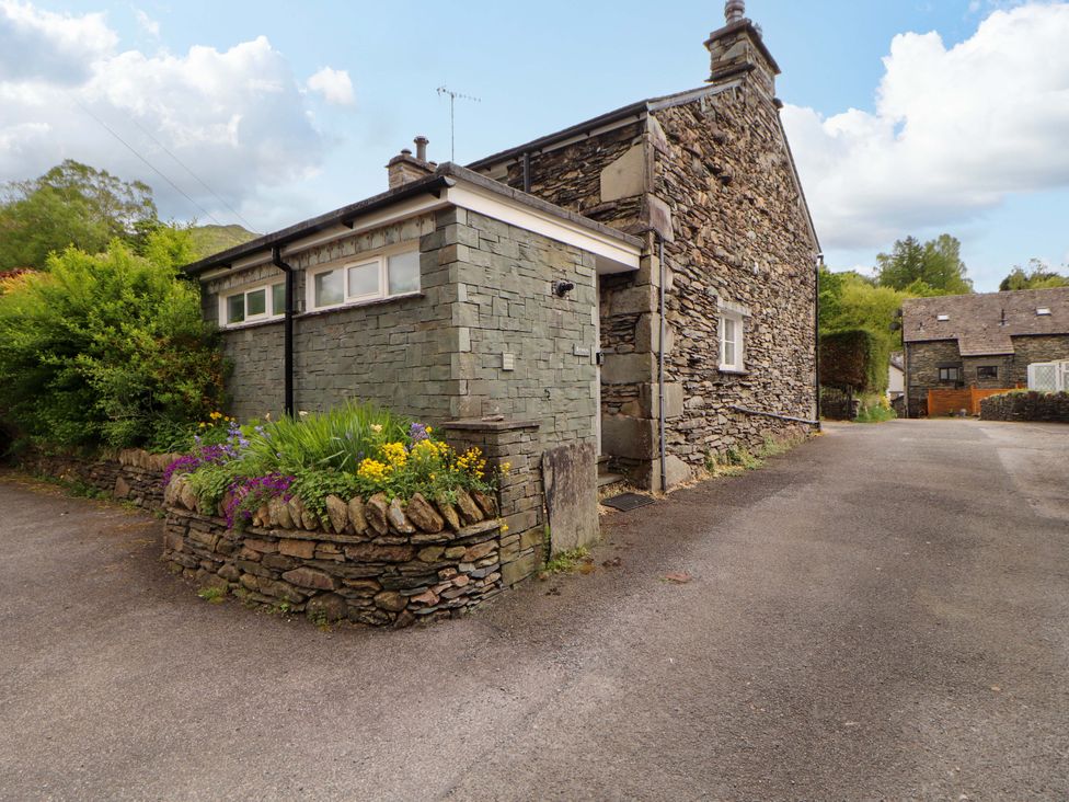 An outdoor view of a stone house with a flower bed at Byways Ambleside