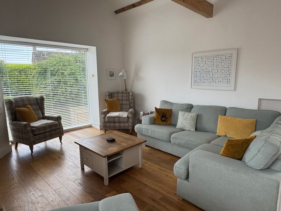 A living room with sofas and armchairs at Old Orchard Barn St. Mellion near St Dominick