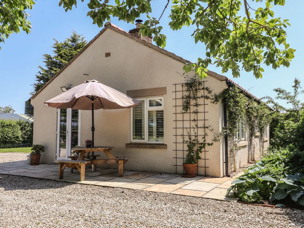 An outdoor area with a table and umbrella at Low Grounds Cottage Harome near Helmsley