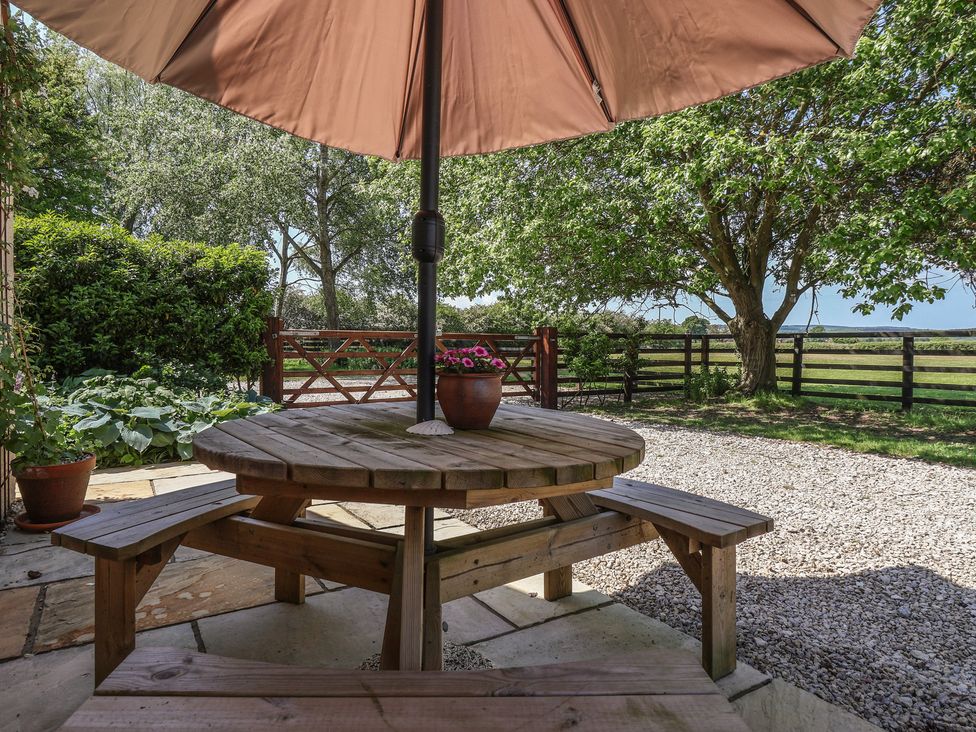 An outdoor seating area with a wooden table and umbrella at Low Grounds Cottage Harome near Helmsley