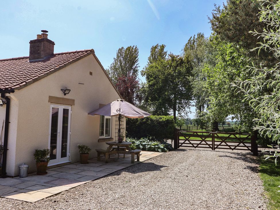 An outdoor seating area with a table and umbrella at Low Grounds Cottage Harome near Helmsley