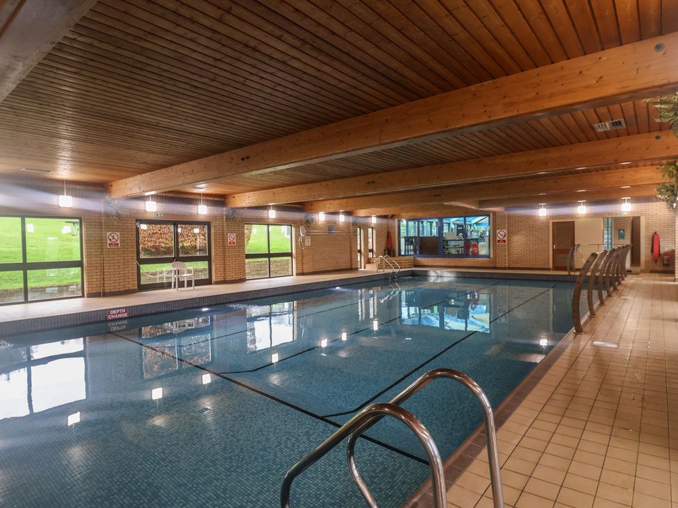 An indoor swimming pool with seating area at Tri-Star House in Charmouth