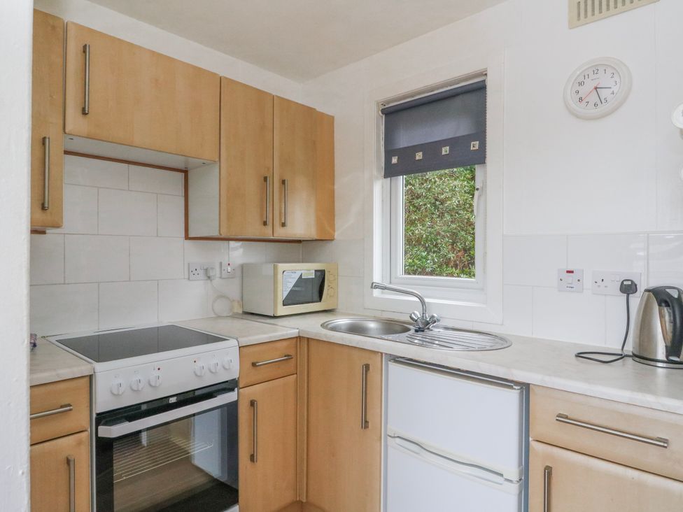 A kitchen with cabinets, stove, sink, microwave at Lochead Chalet Achahoish near Lochgilphead