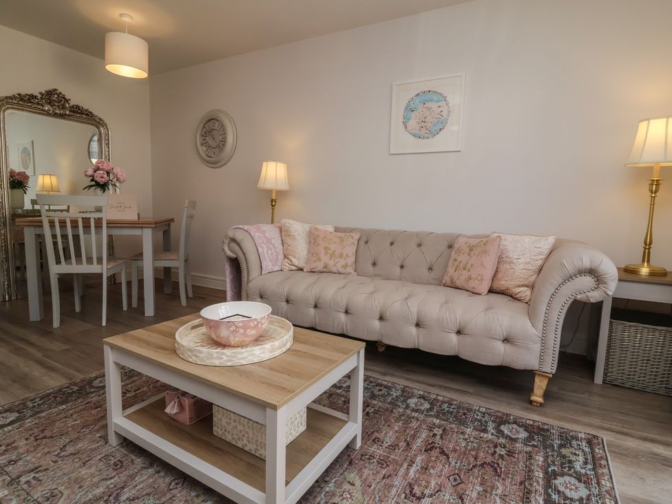 A living room with a sofa and dining area at Seashell Sands in Appledore