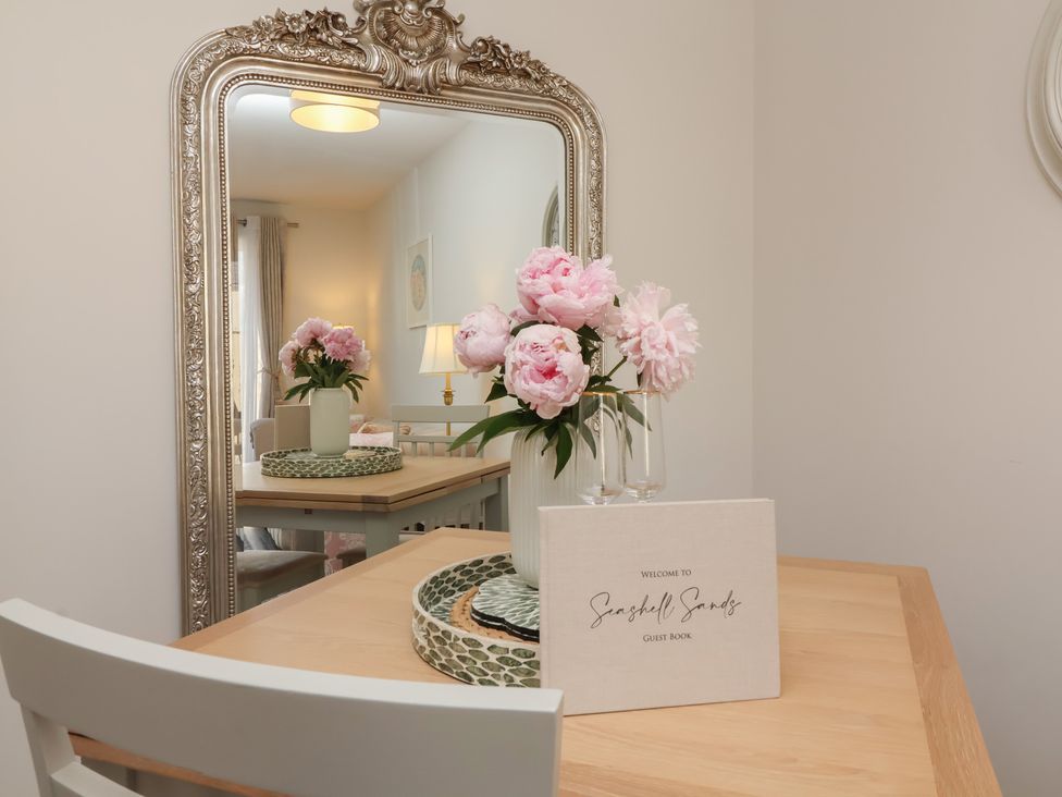 A dining room with a table and flowers at Seashell Sands in Appledore