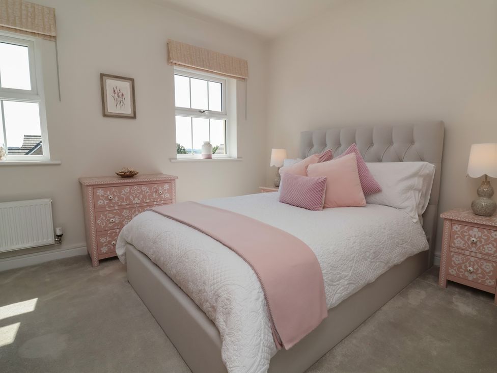 A bedroom with a bed and nightstands at Seashell Sands in Appledore