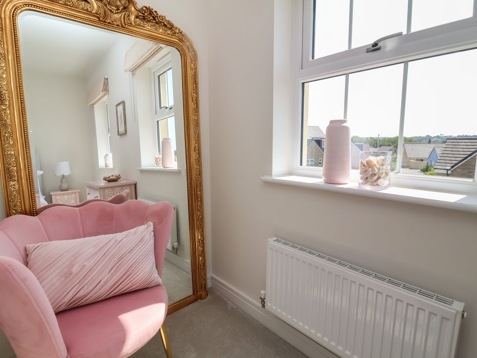 A living room with a pink chair and mirror at Seashell Sands in Appledore
