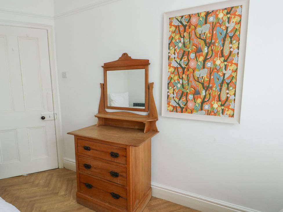 A chest of drawers with a mirror and artwork on the wall at Noah's Rest in Llandudno