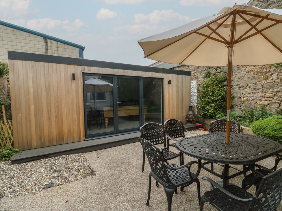 A garden with a wooden cabin and outdoor seating at Noah's Rest in Llandudno