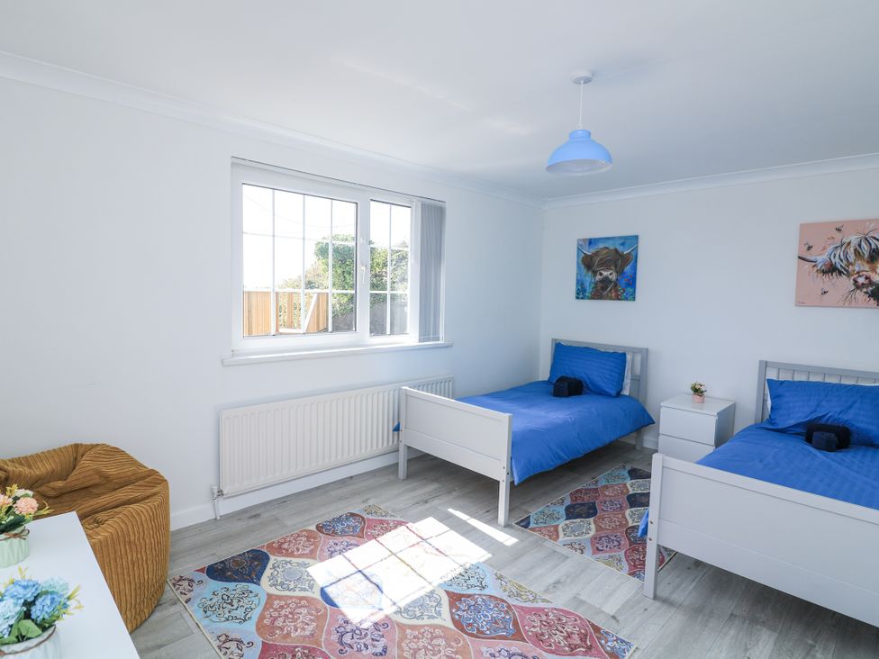 A bedroom with two beds and a rug at Hougoumont Cottage in Torpoint