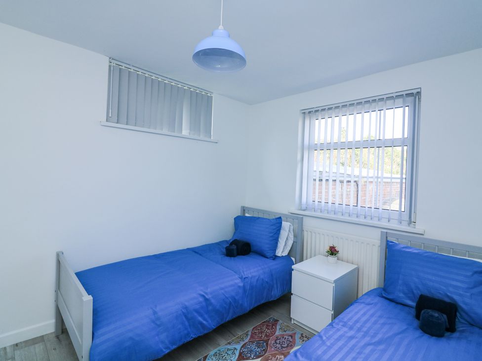 A bedroom with two single beds and a bedside table at Hougoumont Cottage in Torpoint