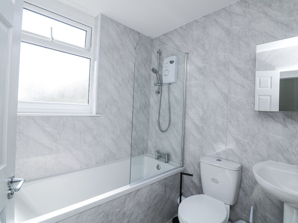 A bathroom with a bathtub, shower, toilet, and sink at Hougoumont Cottage in Torpoint