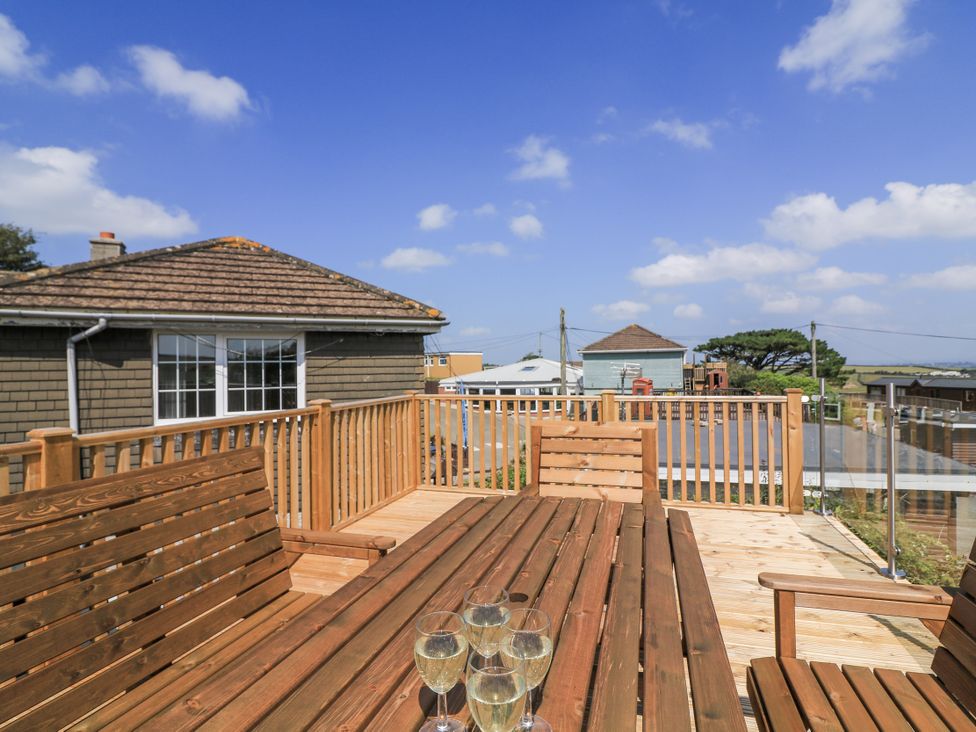 A wooden deck with a table and chairs at Hougoumont Cottage in Torpoint