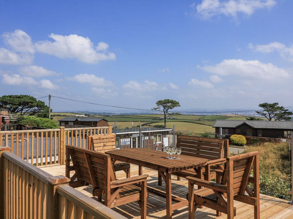 An outdoor patio with a wooden table and chairs at Hougoumont Cottage in Torpoint