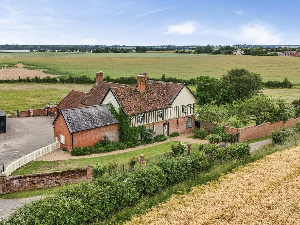 An exterior view of a house with a field and trees at Knights Farm in Harkstead