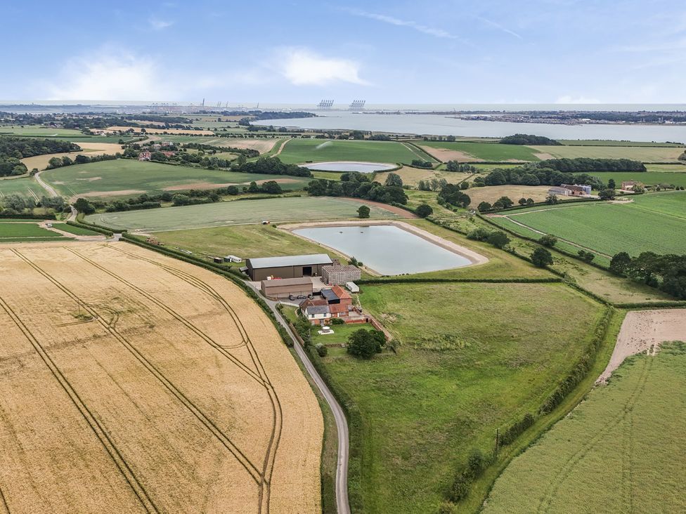 An aerial view of a property with fields and a pond at Knights Farm in Harkstead