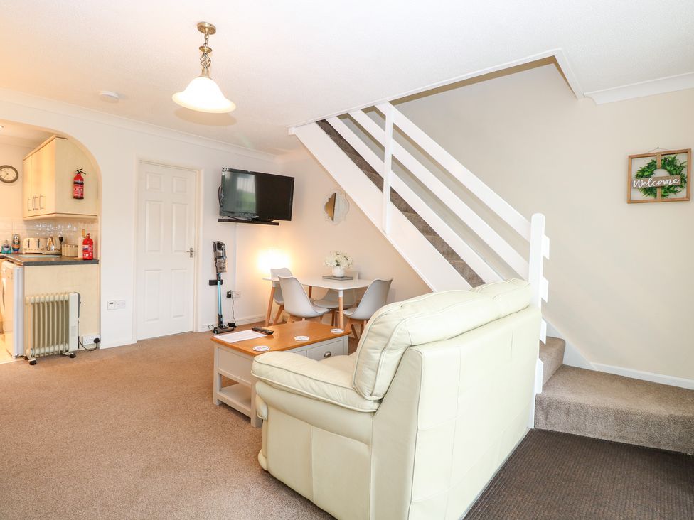 A living room with a sofa and dining area at 19 Waterside Park in Corton