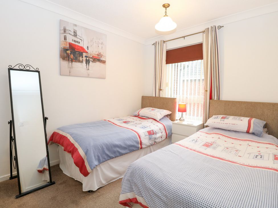 A bedroom with two beds and a mirror at 19 Waterside Park in Corton