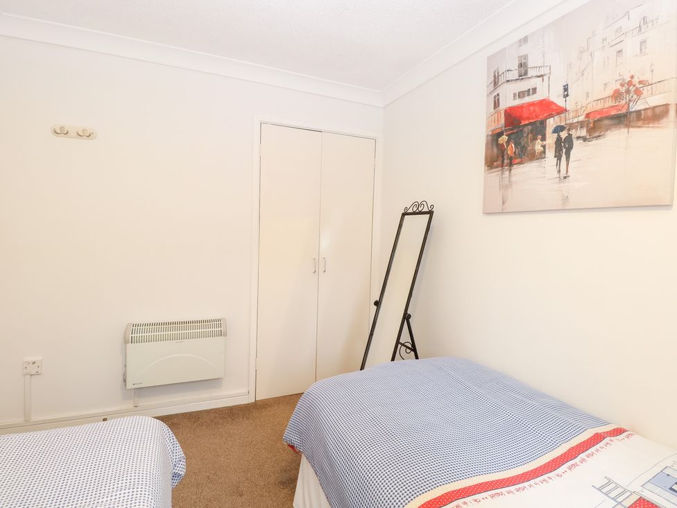A bedroom with two beds and a mirror at 19 Waterside Park in Corton