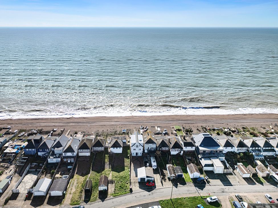 An aerial view of beach huts and vehicles along the shore at Bucket and Spades- Right on the Beach, Pevensey Bay