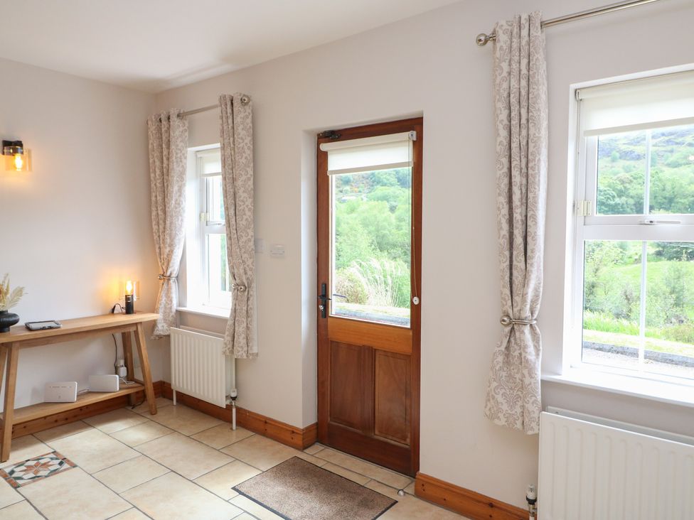 An entrance hall with a table and window curtains at The Skating Rock in Bunane near Kenmare, County Kerry