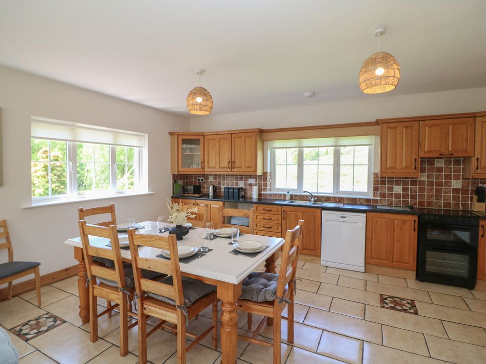 A kitchen with wooden cabinets and dining table at The Skating Rock in Bunane near Kenmare, County Kerry