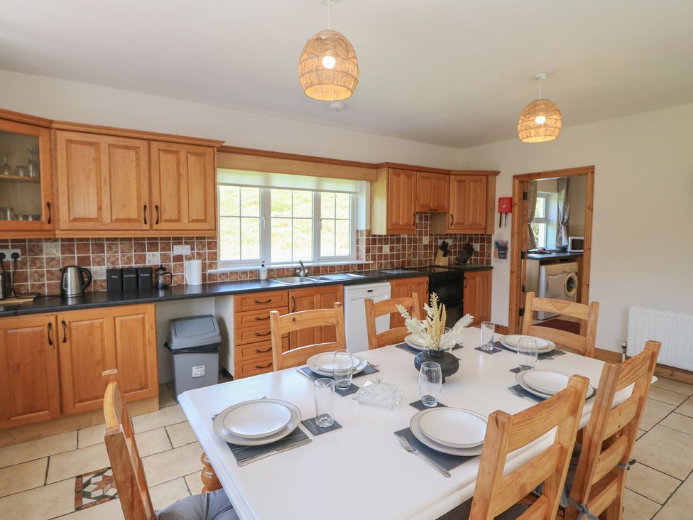 A kitchen with wooden cabinets and dining table at The Skating Rock Bunane near Kenmare, County Kerry