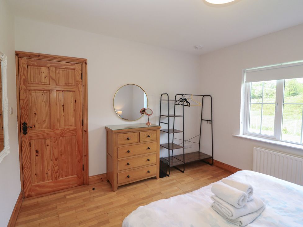 A bedroom with a dresser and clothes rack at The Skating Rock in Bunane near Kenmare, County Kerry