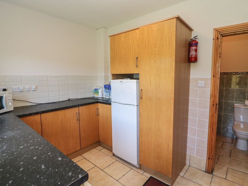 A kitchen with a fridge, microwave, and cupboard at The Skating Rock in Bunane near Kenmare, County Kerry