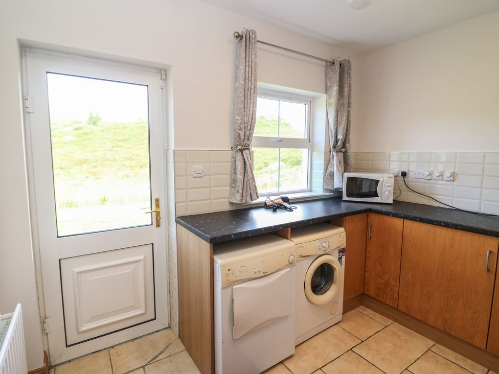 A kitchen with a washing machine and microwave at The Skating Rock in Bunane near Kenmare, County Kerry
