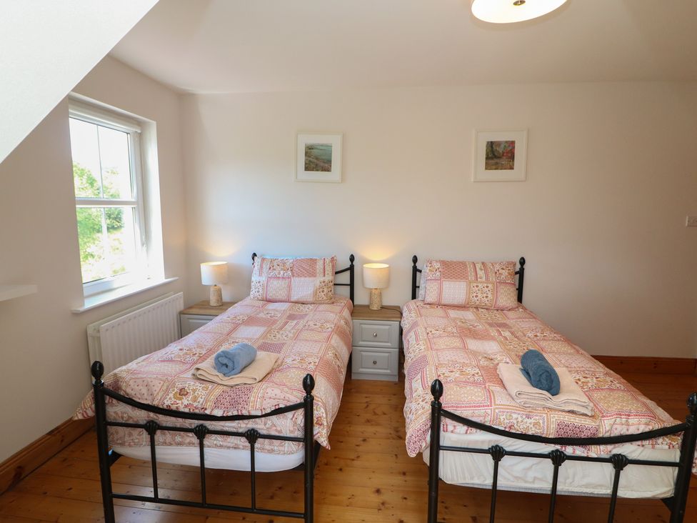 A bedroom with two single beds and lamps at The Skating Rock in Bunane near Kenmare, County Kerry