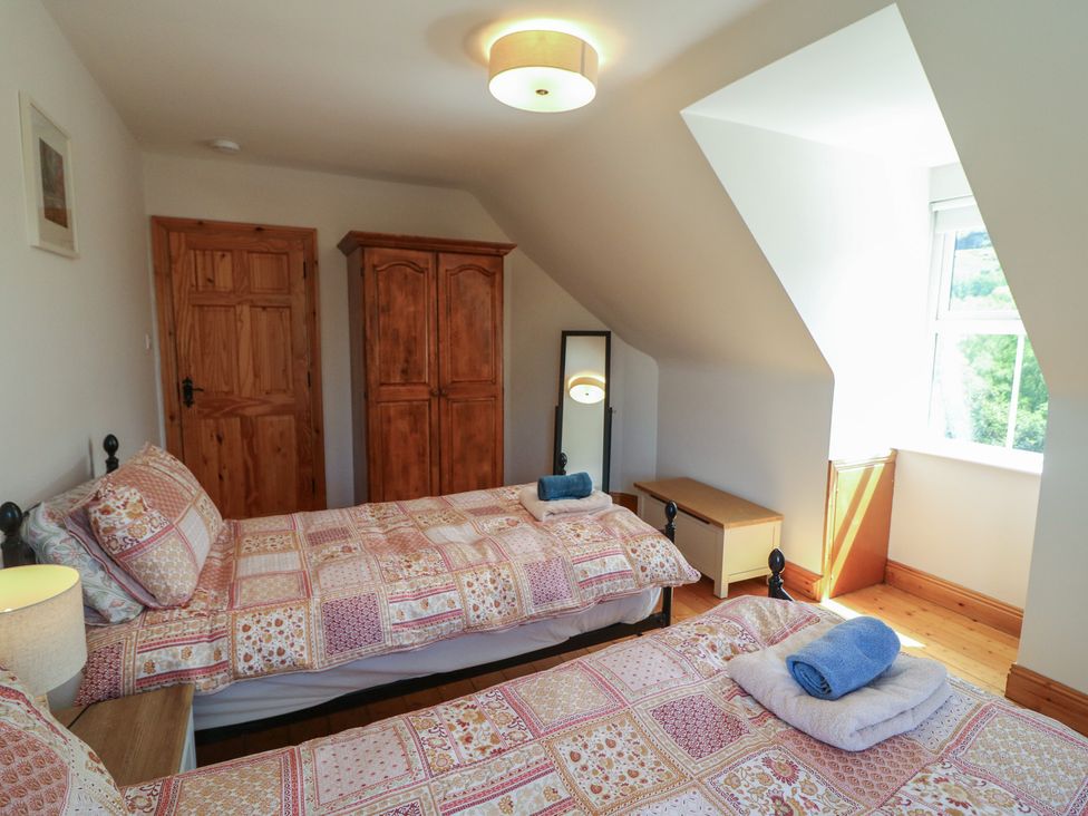 A bedroom with two beds and a wardrobe at The Skating Rock in Bunane near Kenmare, County Kerry