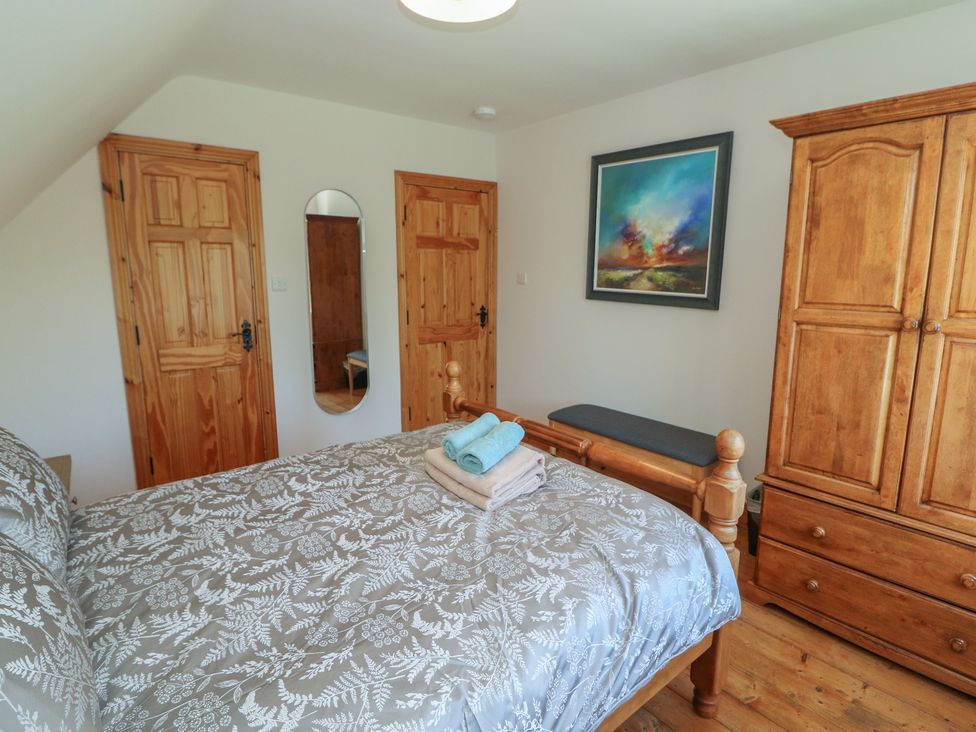 A bedroom with a bed, wardrobe, and mirror at The Skating Rock in Bunane near Kenmare, County Kerry