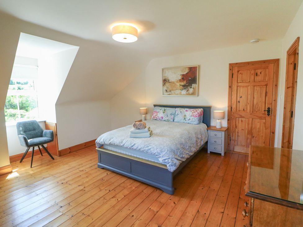 A bedroom with a bed and chair at The Skating Rock in Bunane near Kenmare, County Kerry