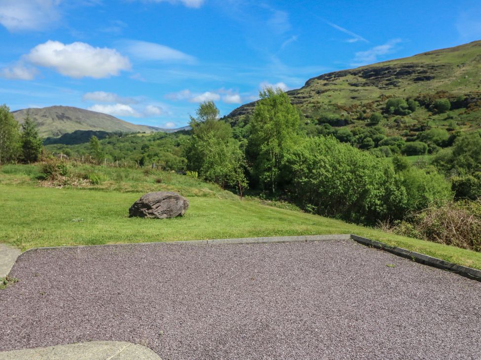 A view of a grassy area with a rock and mountains at The Skating Rock in Bunane near Kenmare, County Kerry